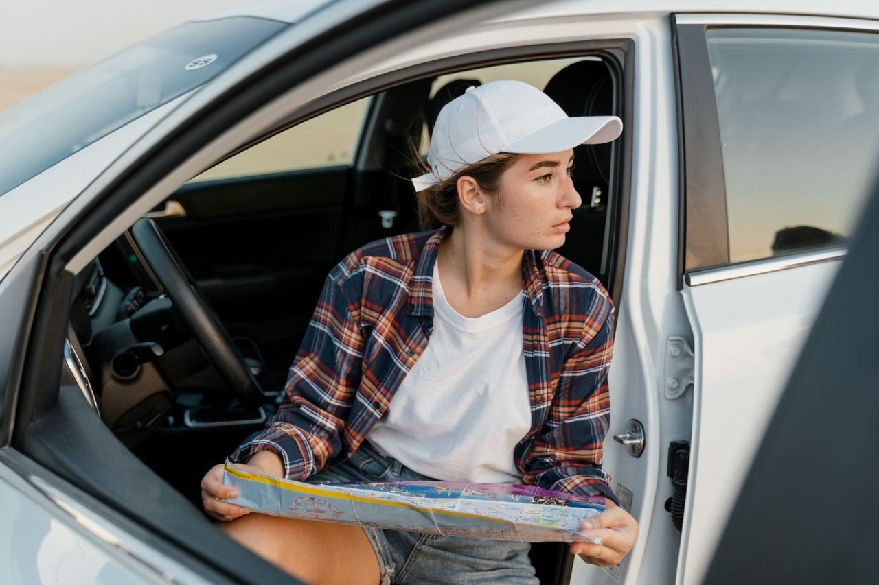 devojka viri iz automobila i gleda mapu